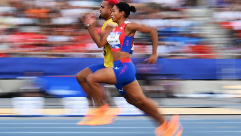 A female athlete running on a track next to her male guide