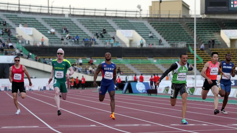 A man crossing the finish line in an athletics race ahead of five competitors