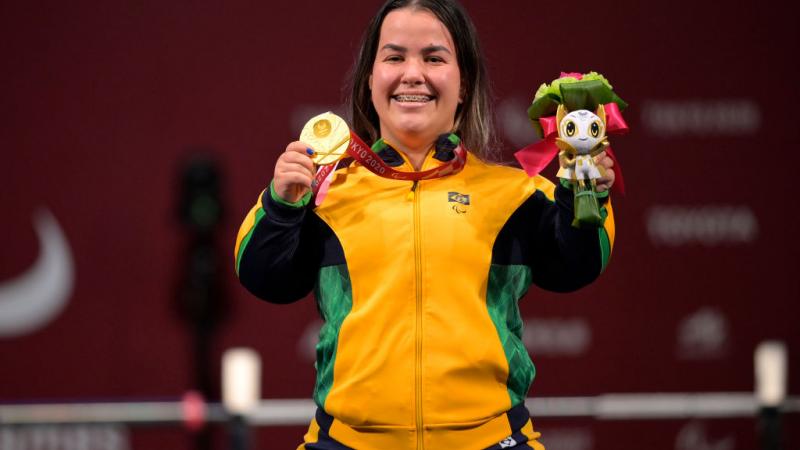 A female Para powerlifter poses for a photo after receiving a gold medal.