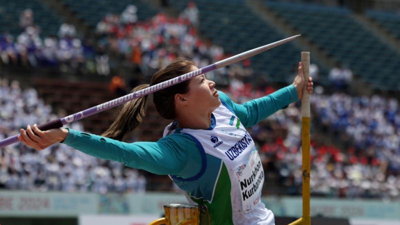 A female athlete throwing a javelin in a stadium