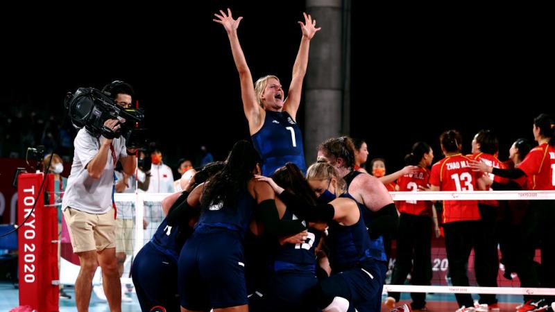 The female sitting volleyball players gather and celebrate on court at the Tokyo 2020 Paralympics