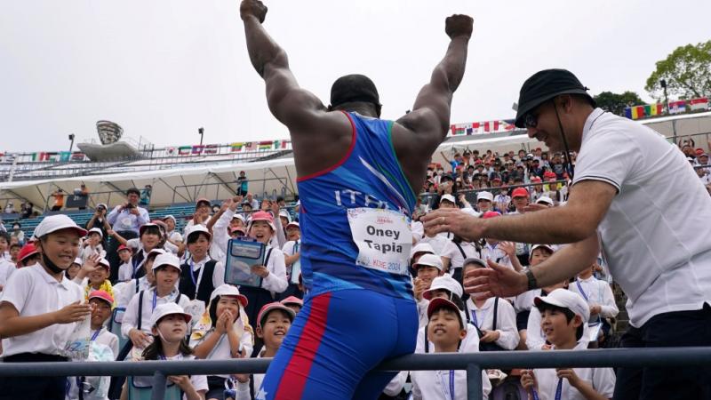 A man waving to a group of children in a stadium stand