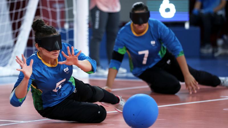 A female athlete tries to block a ball in front of the goalball net