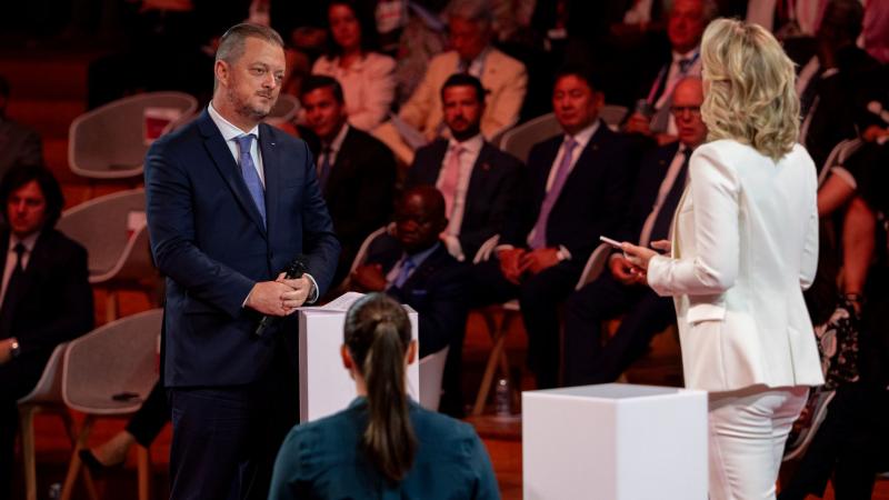Andrew Parsons, IPC President, stands on the stage with two participants. People 