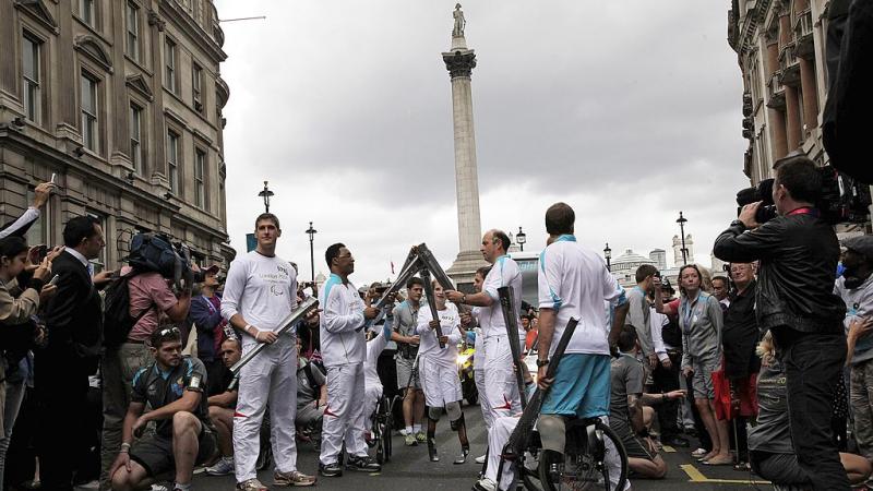 a group of Para athletes lighting a torch in front of Nelsons Column 