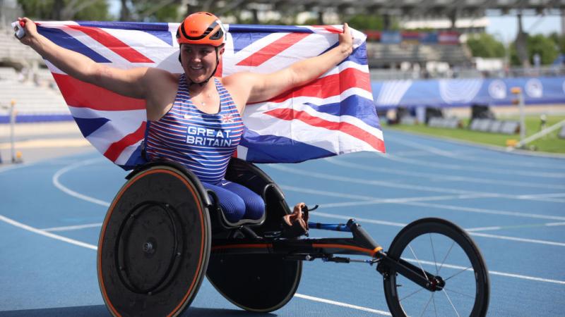 Wheelchair racer Eden Rainbow-Cooper holds up the Great Britain flag in celebration 