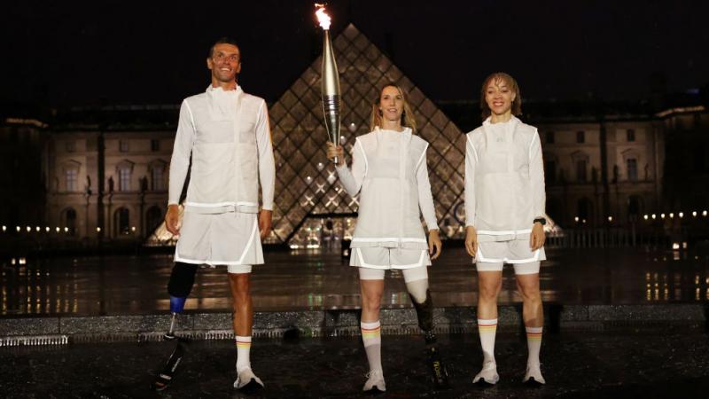 Marie-Amelie Le Fur holds the Olympic Torch in front of the Louvre