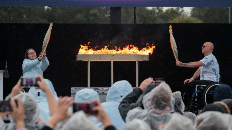 two Paralympians in wheelchairs holding up Paralympic torches