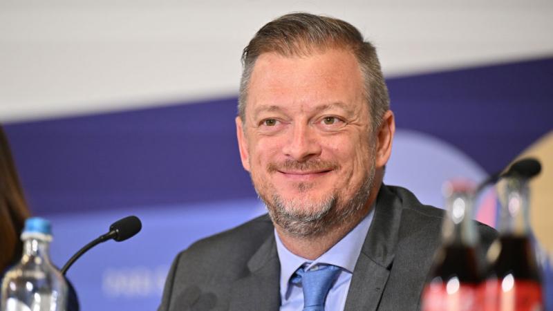 IPC President Andrew Parsons smiling in front of a microphone