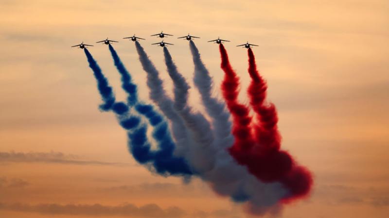 A group of planes flying in formation displaying coloured smoke