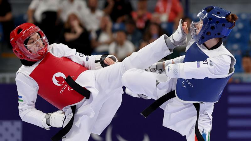Two Para taekwondo competitors face each other at Paris 2024, one wearing red the other blue 