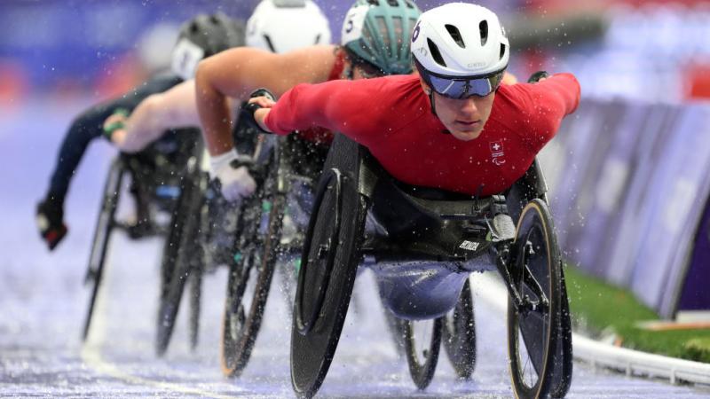 A female wheelchair racer leading the pack ahead of three competitors