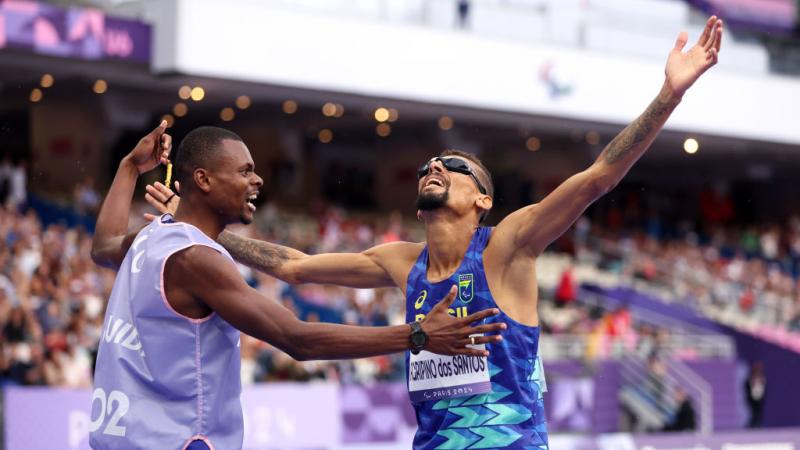 Agripinos dos Santos and his guide raise their arms in celebration
