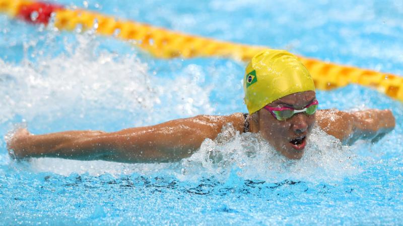 Brazilian swimmer Maria Carolina Santiago competes. She is wearing a yellow swimming cap and pink goggles