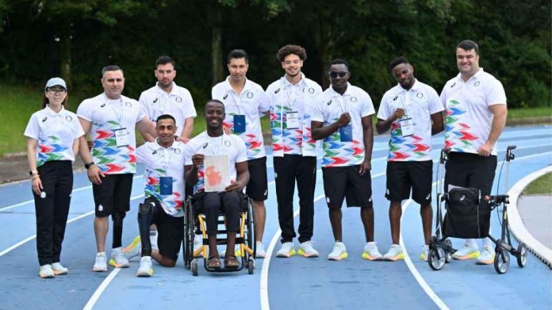 the Refugee Paralympic Team sitting and standing on an athletics track 