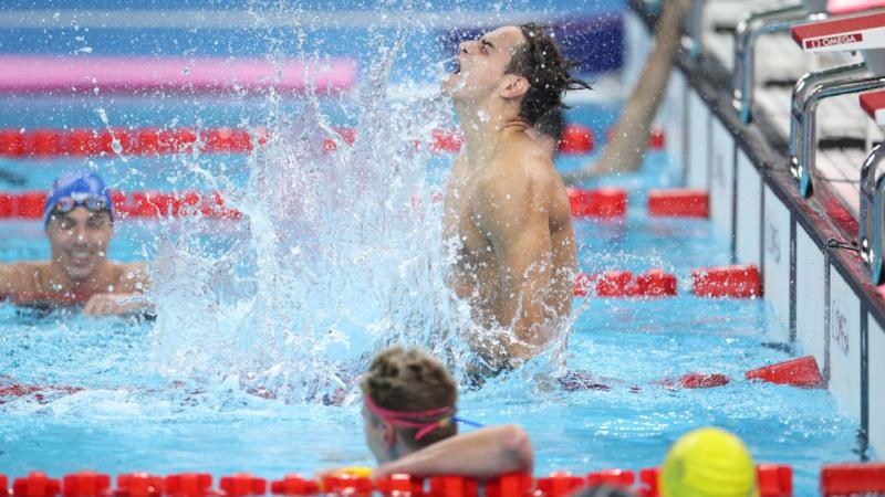 A swimmer celebrating in the water observed by three other swimmers