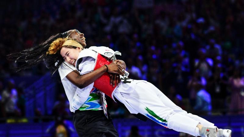 Coach Haby Niare lifts up Zakia Khudadadi, a female Para taekwondo athlete, to celebrate