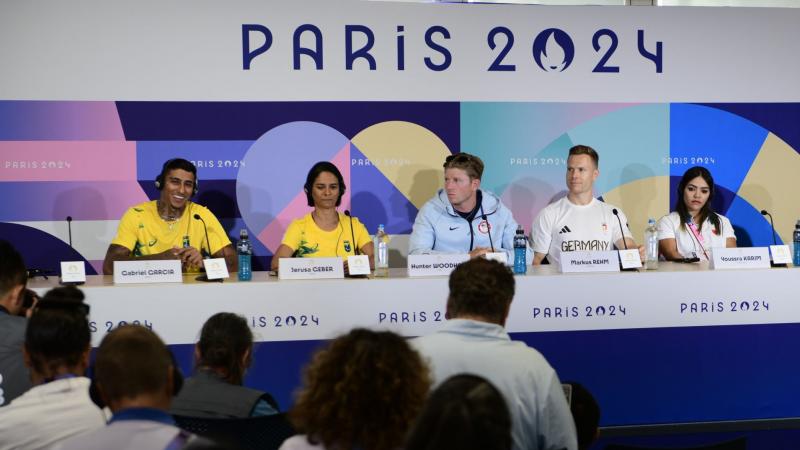 A group of three men and two women in a press conference