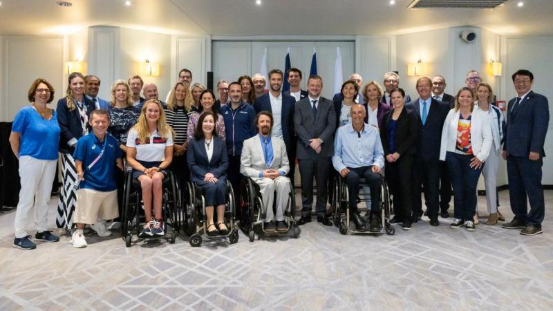 A group of people both standing and in wheelchairs smile together
