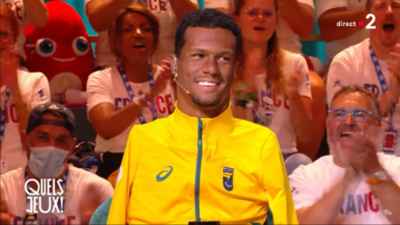 Una captura de pantalla de televisión de un atleta en un estudio con aficionados franceses