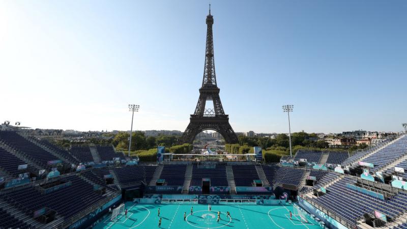 An outdoor blind football stadium, with the Eiffel Tower in the background