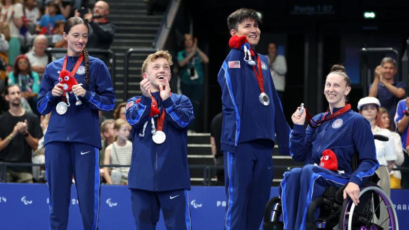 A group of USA Para swimmers smiling on the podium 