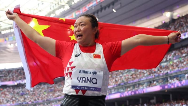 A female athlete with the Chinese flag in a packed stadium