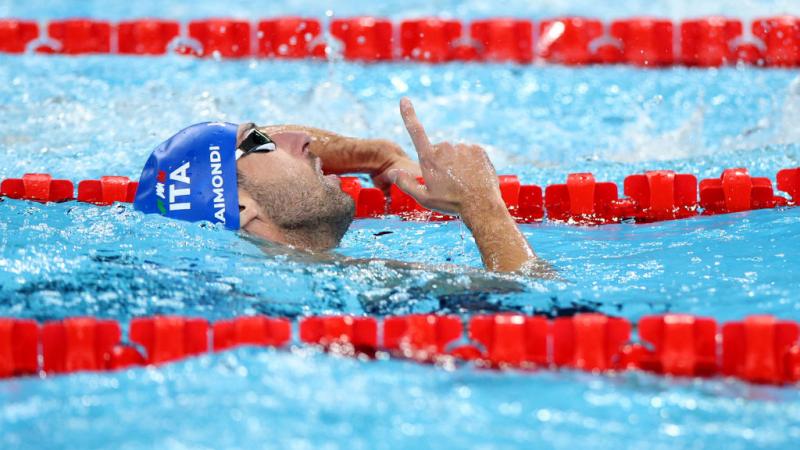 A male swimmer point his finger upwards in the pool