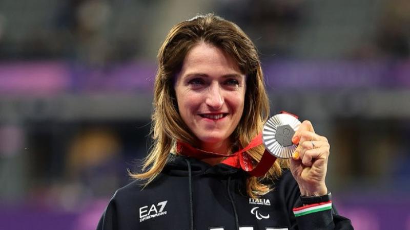 Para athlete Martina Caironi smiles and holds up a silver medal 