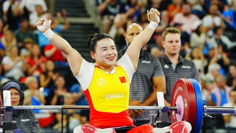 An athlete lifts her hands to celebrate after a successful lift
