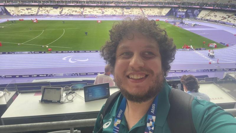 Harry De Cosemo, a male reporter, takes a selfie in front of the purple tracks at the Stade de France