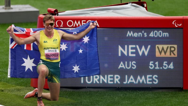 James Turner poses for a photo in front of the board that shows he broke the world record.