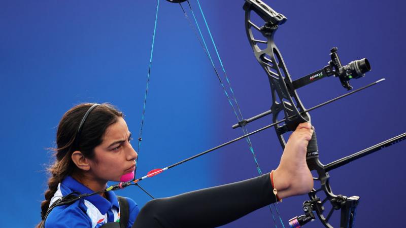 A female Para athlete prepares her bow with her right foot