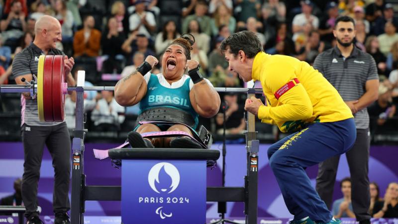 Tayana Medeiros pumps her fist after a successful lift