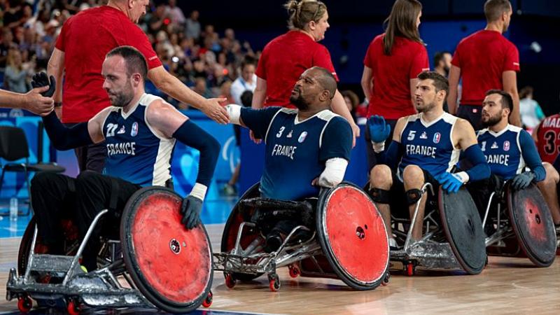 Four wheelchair rugby players form a line to shake hands with officials
