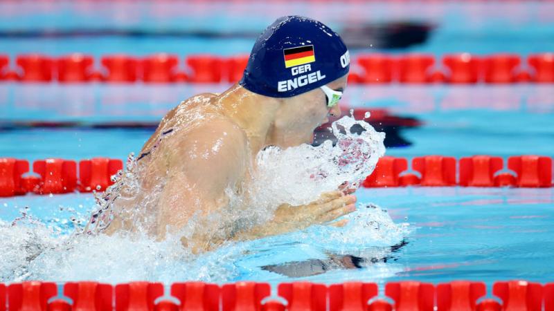 A male athlete with a cap of Germany swimming breaststroke