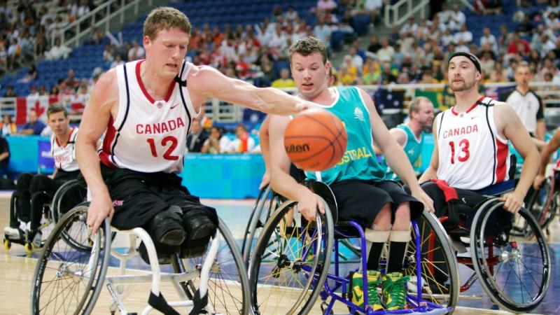 A male wheelchair basketball player is dribbling the ball