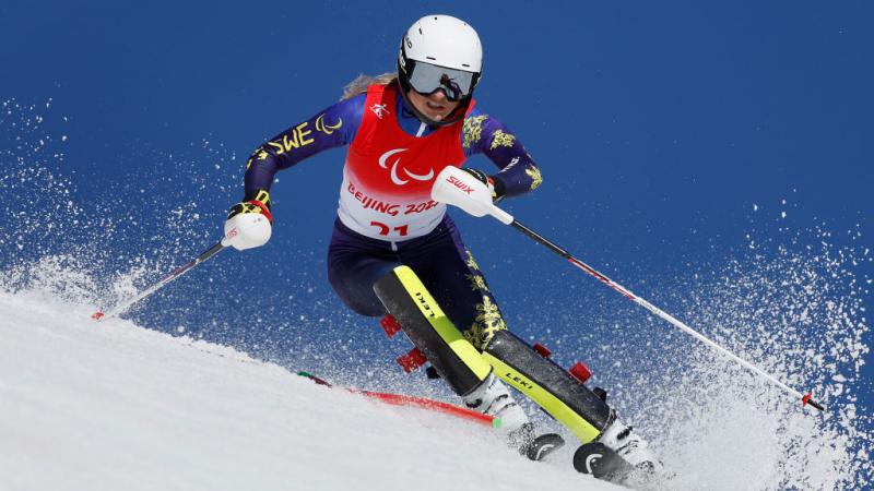 A female Para alpine skiing athlete in action.