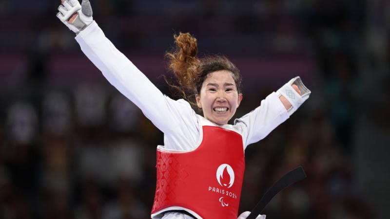 A female Para taekwondo athlete is celebrating.