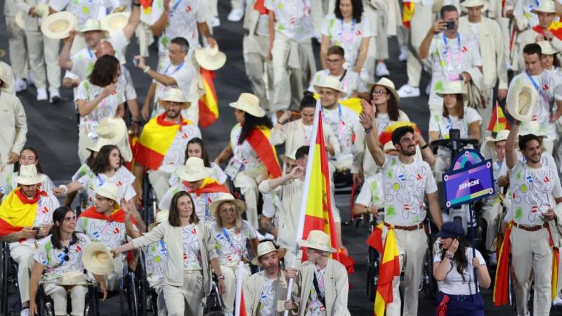 A large group of athletes taking part in the Parade of Nations at the Paris 2024 Opening Ceremony. They are holding the Spanish flag