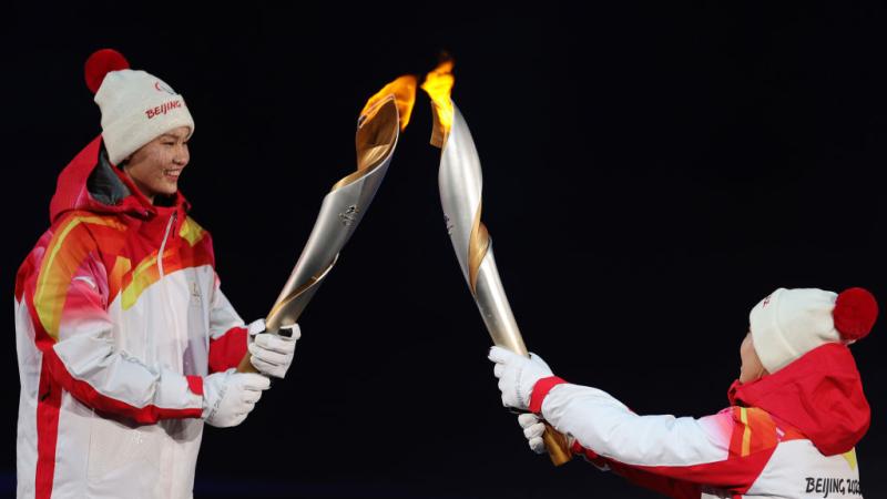 Two people carrying the Paralympic torch during the Opening Ceremony of the Beijing 2022 Paralympic Winter Games. 
