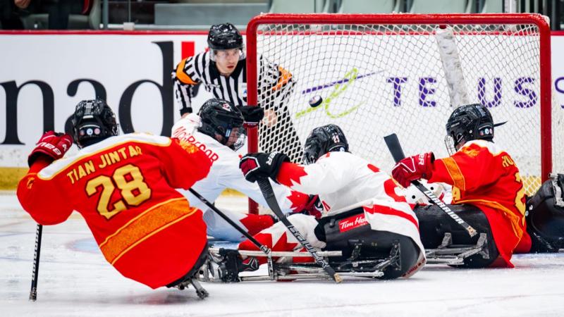 A Para ice hockey official watching four players