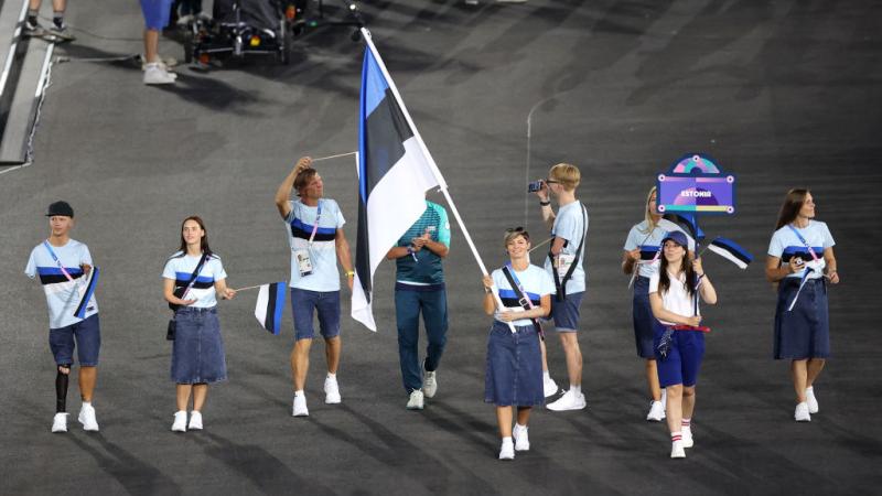 Seven male and female athletes take part in the Parade Of Nations at the Paris 2024 Opening Ceremony. A female athlete is carrying the Estonian flag.