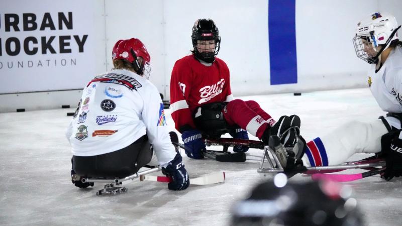 Three women on sledges in an ice rink