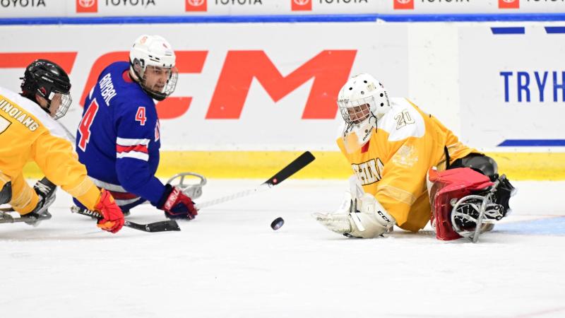 A Team USA Para ice hockey player against two Chinese players