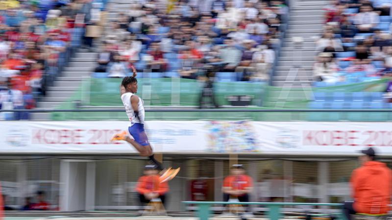 A man competing in the long jump in front of the crowd in a stadium