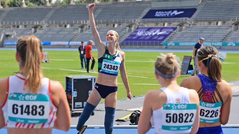 A female athlete with prosthetic legs waving from a track