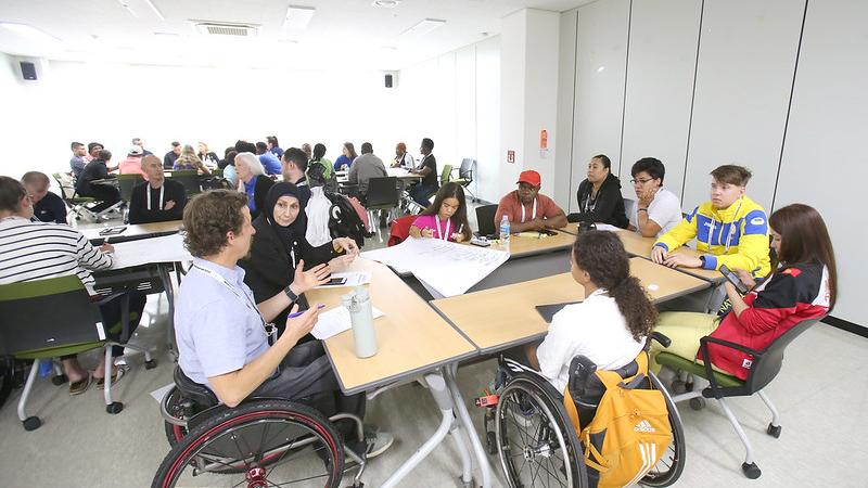 Nine athletes gather around a table for a discussion during the athletes' forum in 2023