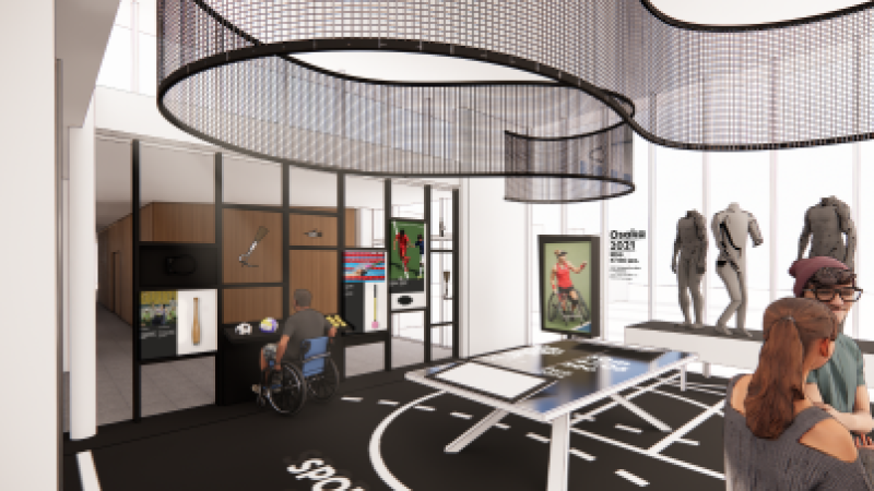 Multiple elements, including a table tennis table in the middle of a room surrounded by playful shelfs with sports equipment, apparel, prosthetics and screens.