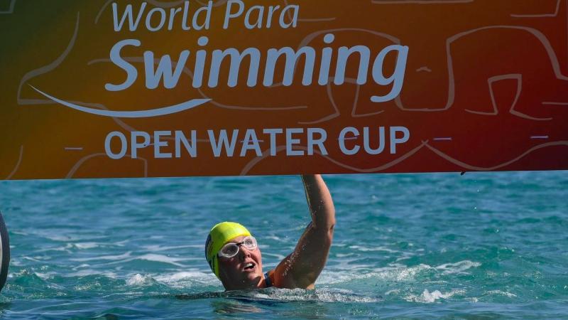 A female swimmer hitting the board at the finish line of the World Para Swimming Open Water Cup